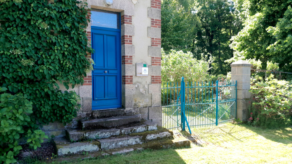 Voorkant van woonhuis L'école Buissonnière met blauwe deur en klimop.